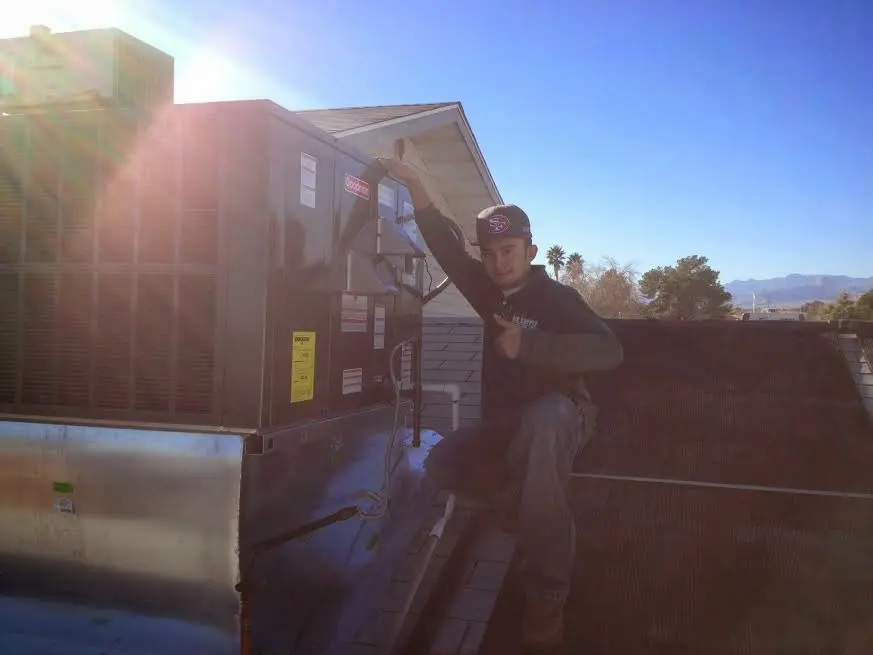 HVAC technician performing Air Duct Cleaning on a rooftop unit in Rogers